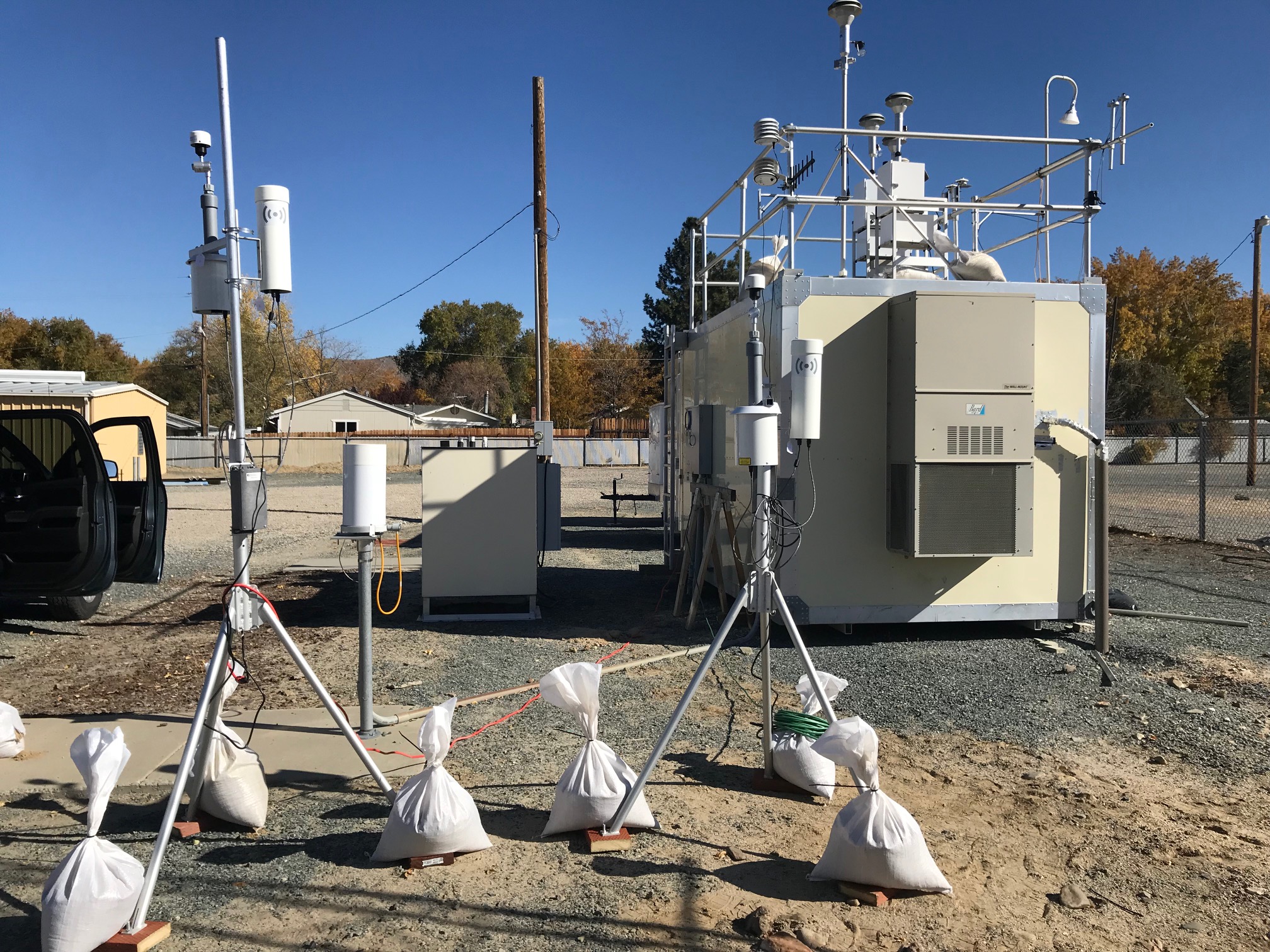 An image showing two portable air sensors and one permanent air quality monitoring station.